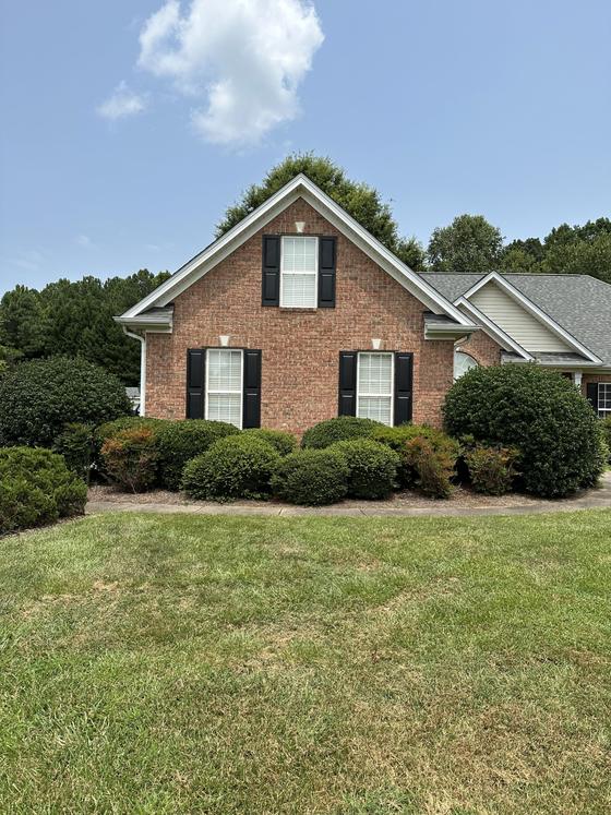 Brick home exterior with black shutters and landscaped front yard