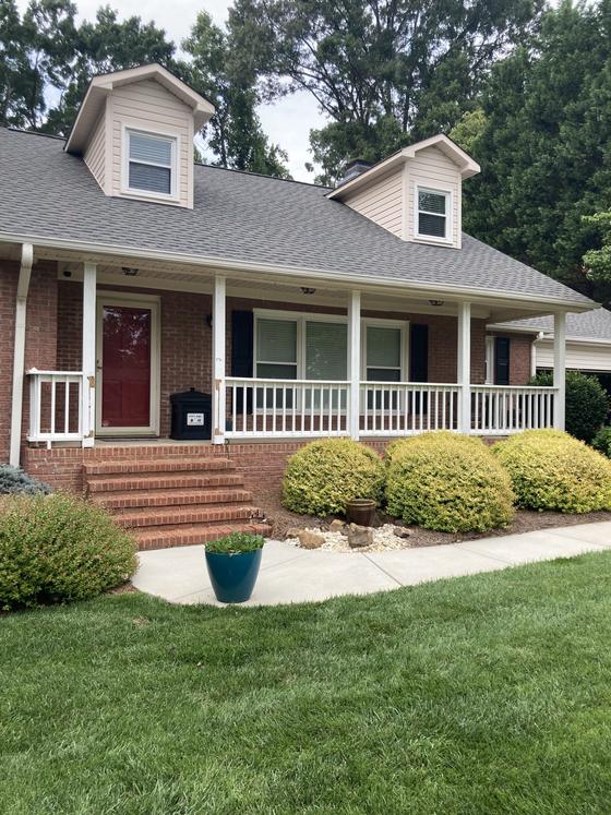 Brick home with a white front porch, dormers and new landscaping