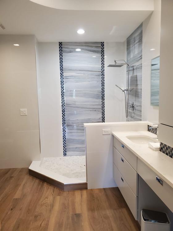 Walk-in shower with a vertical blue accent tile column and a white vanity