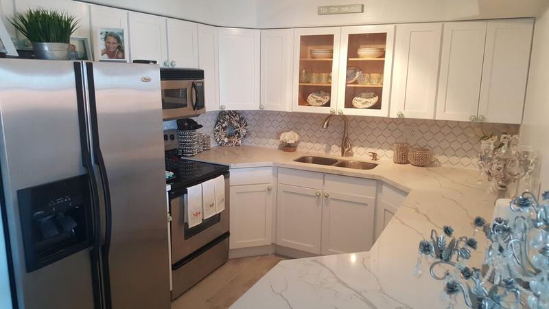 Kitchen with marble-look countertops, white cabinets and stainless appliances