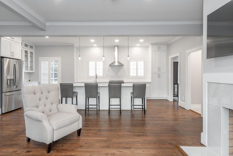 Kitchen open to the living room with a tufted armchair and recessed lighting