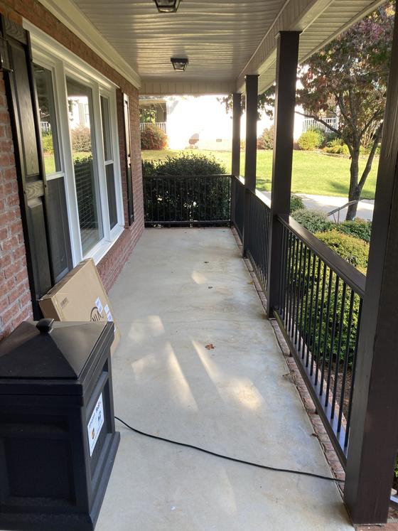 Covered porch with dark wood columns and a metal railing